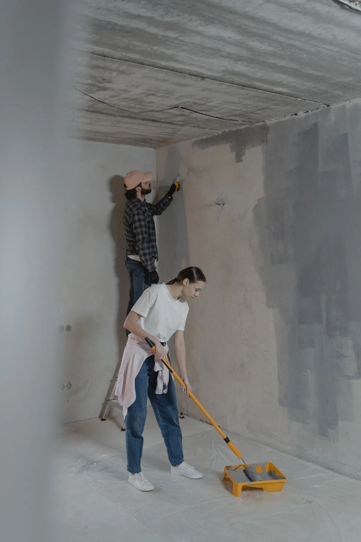 Deux peintres appliquant une sous-couche au rouleau sur des murs neufs